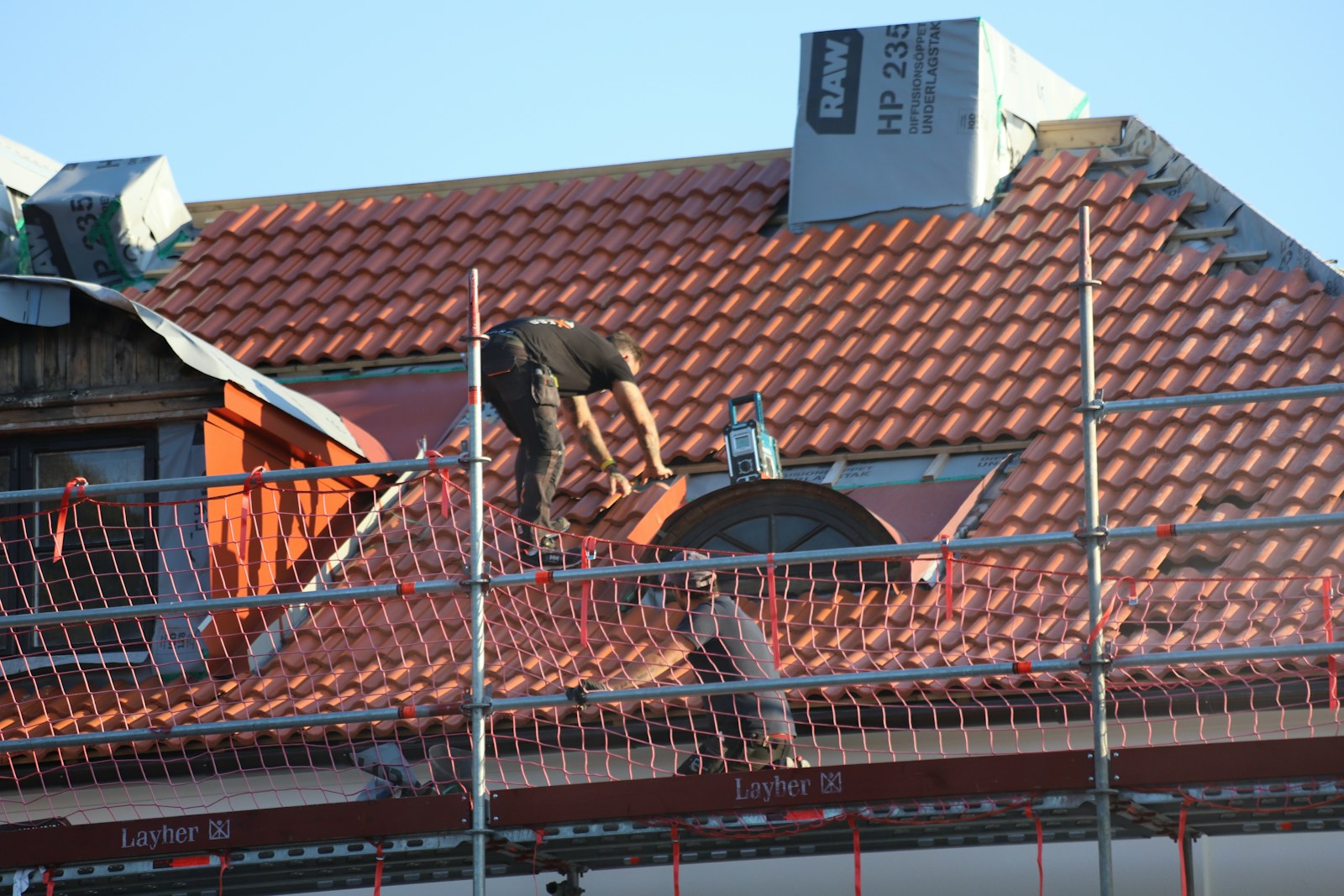 Roofing professional inspecting an asphalt-shingle roof