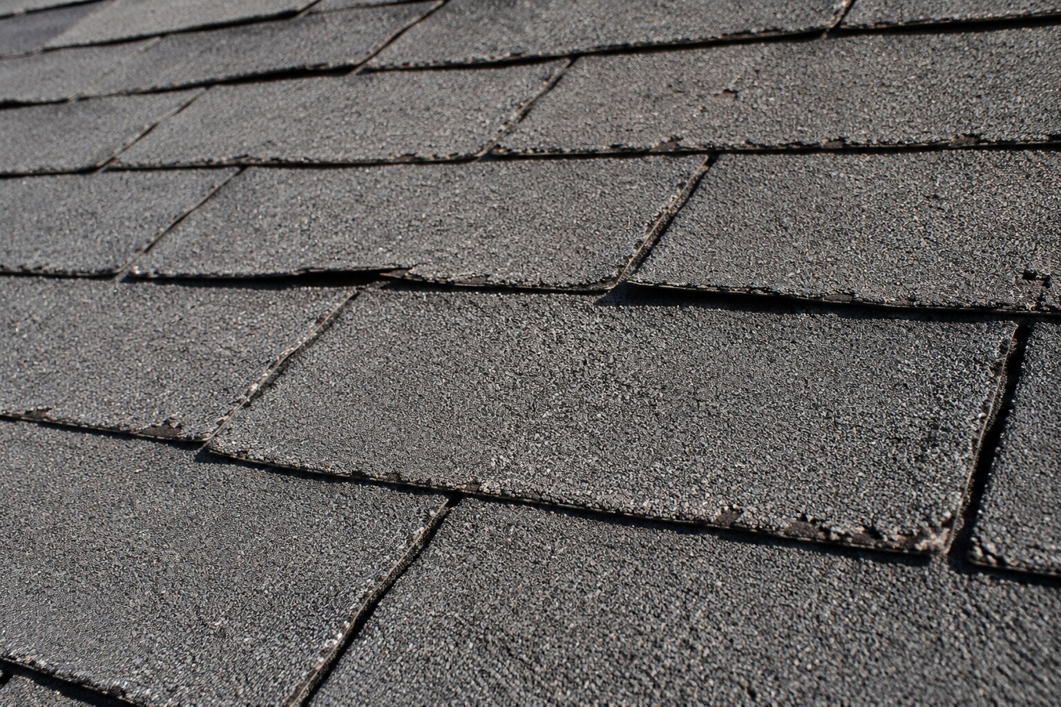 Close-up of old, dry asphalt shingles with curled edges