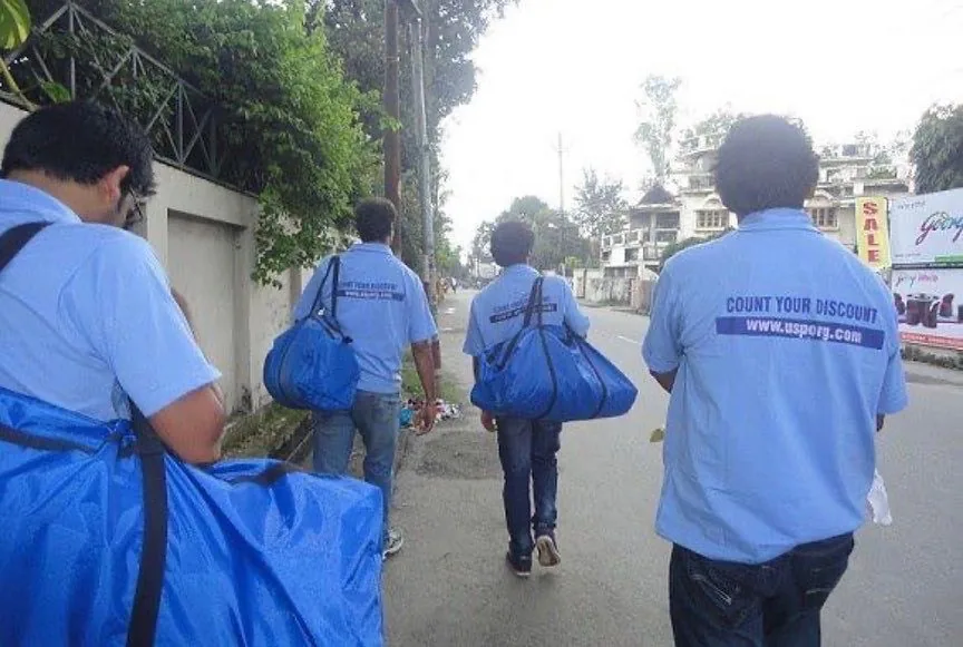 Saurabh Bhatnagar and his team carrying coupon-book bags along a road